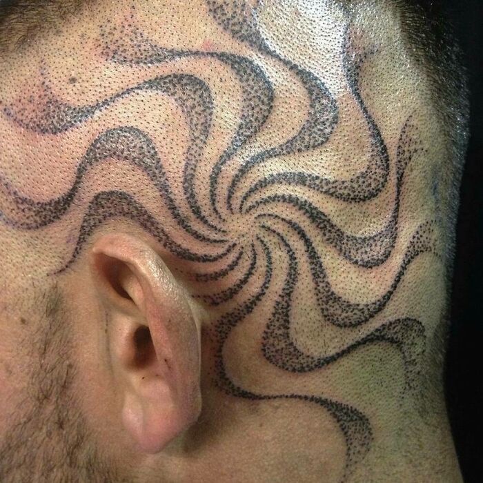 Optical illusion tattoo with swirling patterns on the side of a person's shaved head.