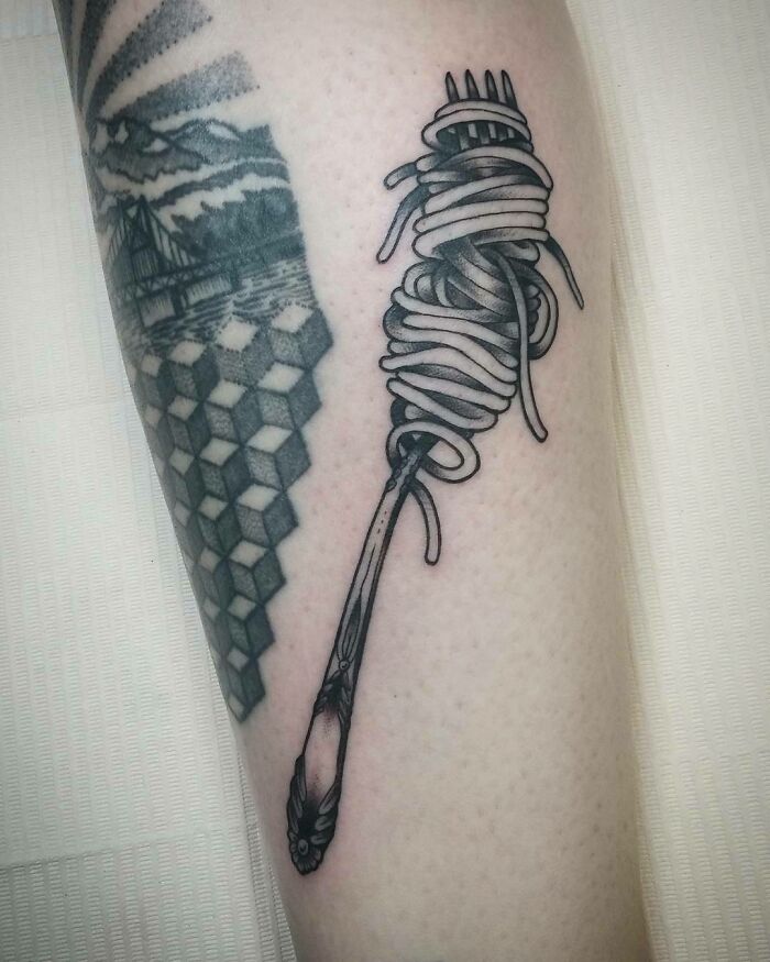 Fork and spaghetti tattoo illustrating food inspiration on skin.