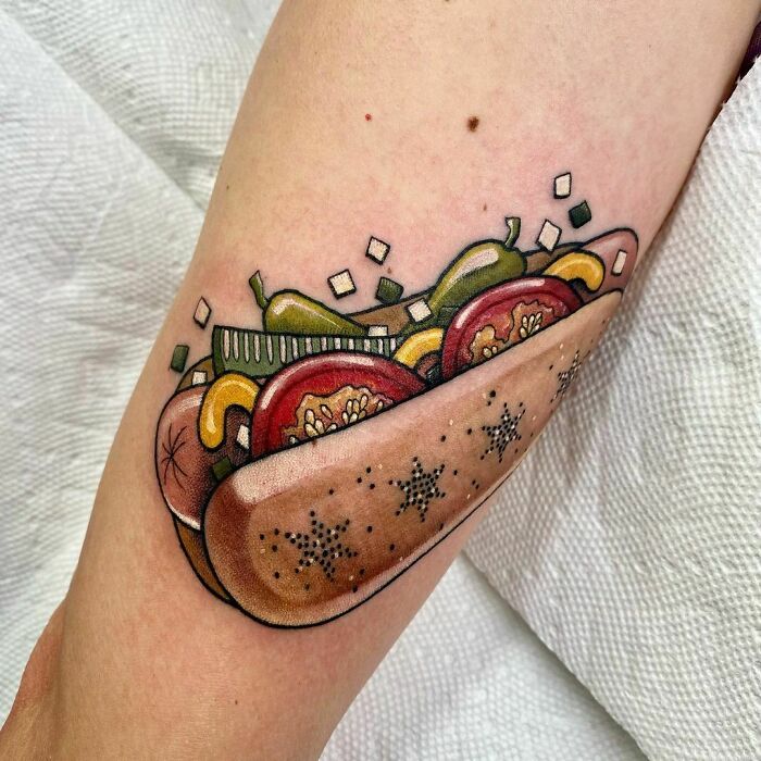 Watercolor hot dog tattoo on arm featuring vibrant toppings for food tattoo inspiration.