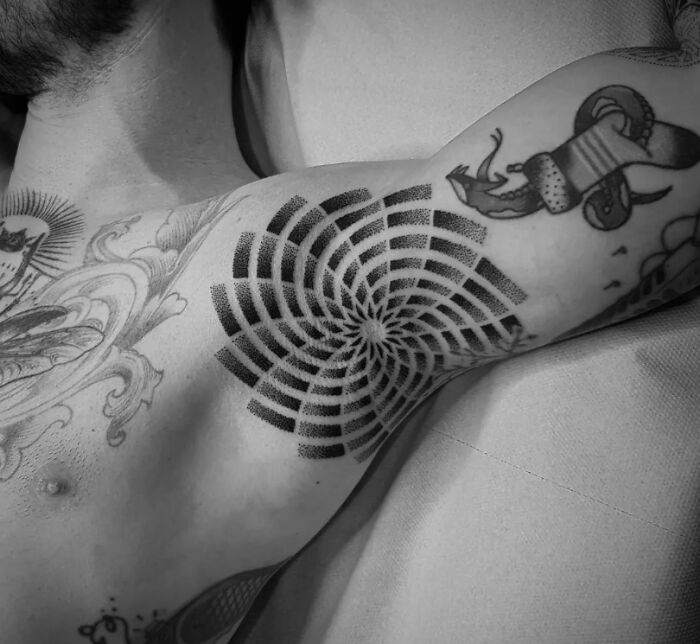 Optical illusion tattoo on a person's arm creates a dynamic, swirling pattern that plays tricks on the eyes.
