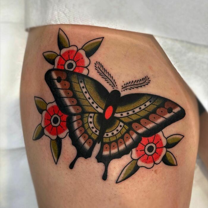 American traditional tattoo of a butterfly with red flowers on the arm.