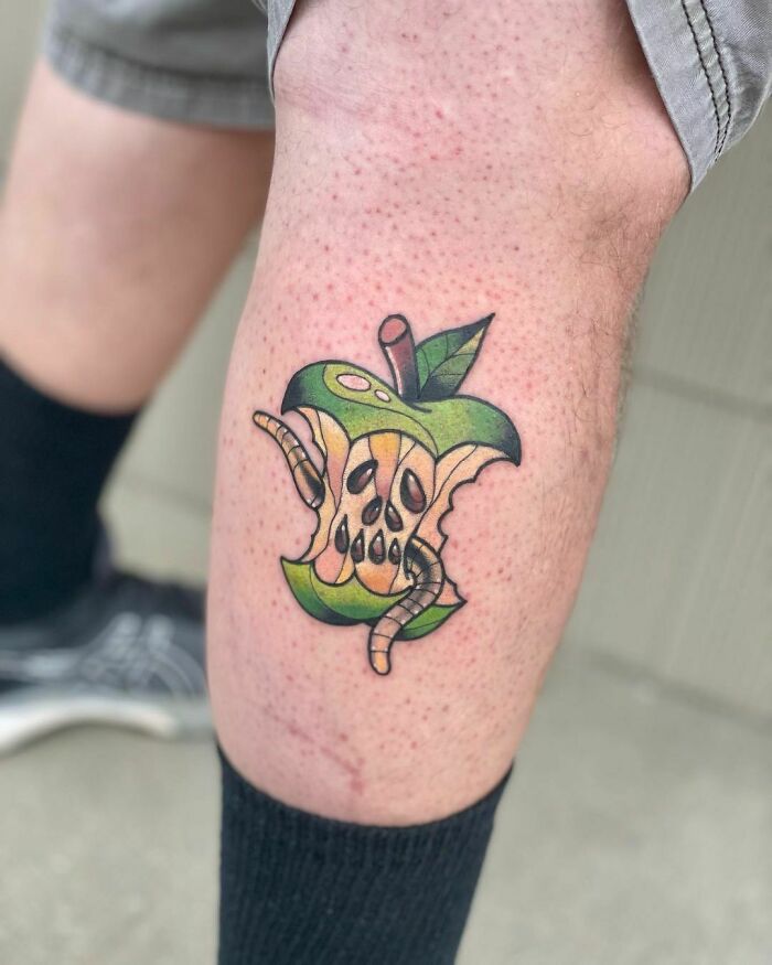 Watercolor tattoo of a bitten apple with a worm, showcasing unique food tattoo inspiration.