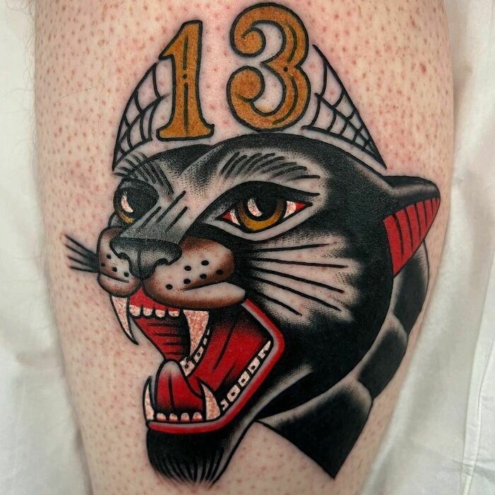 Black panther American traditional tattoo with the number 13 on a person's skin.