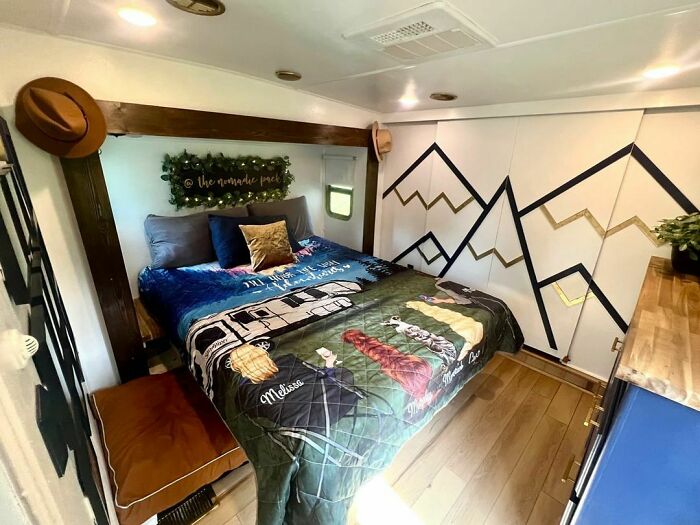 Cozy tiny house bedroom with a colorful camper-themed bedspread and mountain wall design.