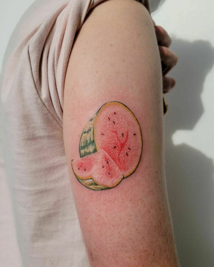Watermelon watercolor tattoo on arm, showcasing vibrant food-inspired ink design.
