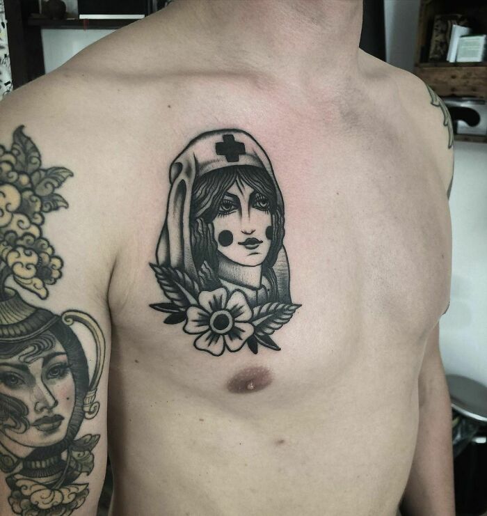 American traditional tattoo of a nurse with a flower on a man's chest.