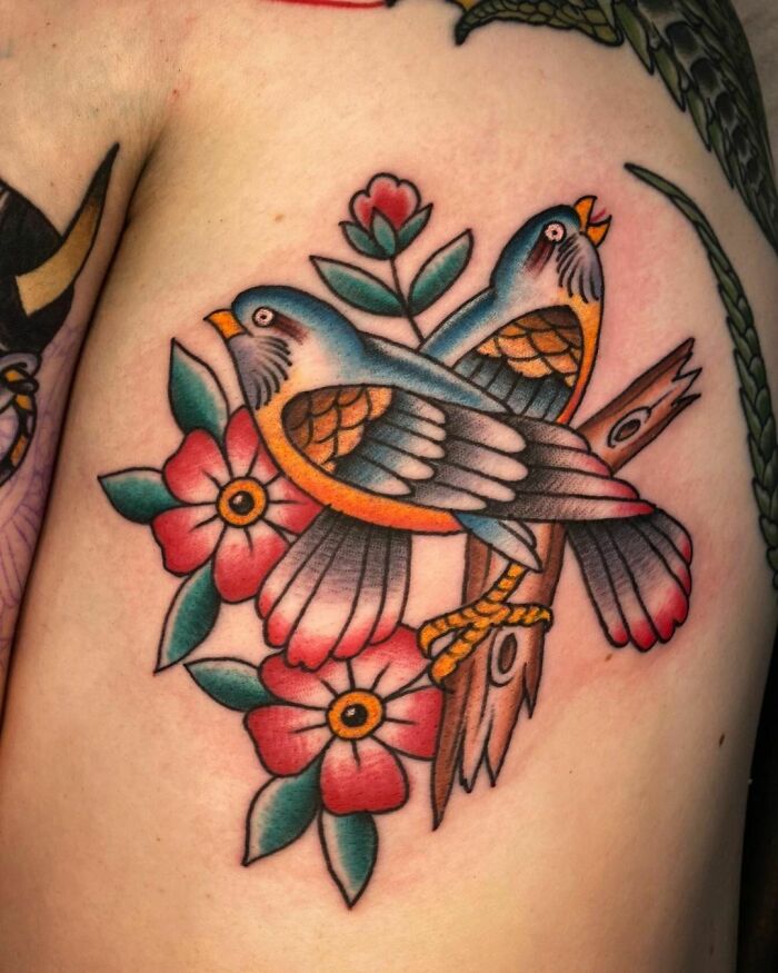 Two birds with flowers in an American traditional tattoo design on the shoulder.