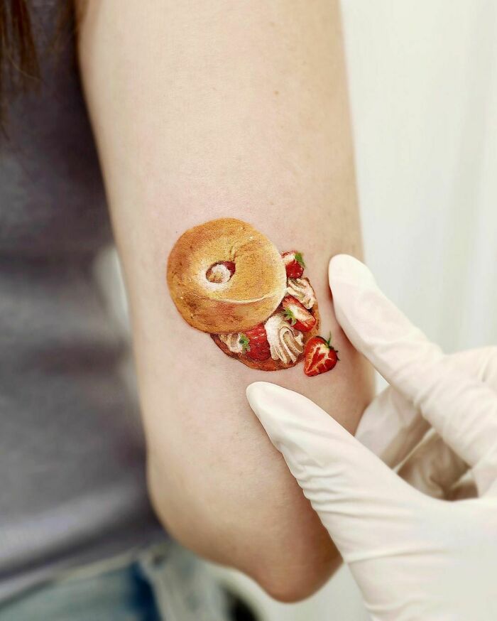 Watercolor tattoo of a strawberry cream bagel, showcasing food tattoo inspiration.