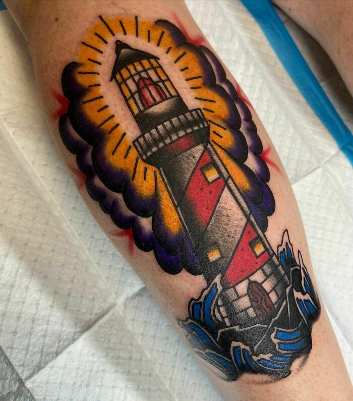 American traditional tattoo of a lighthouse surrounded by purple clouds and waves.