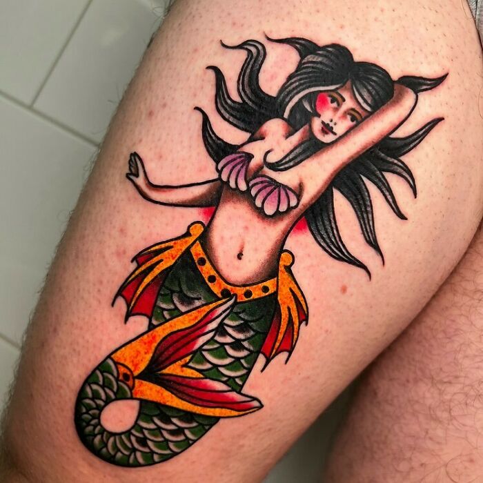 American traditional tattoo of a mermaid with bold colors and classic design on a person's skin.