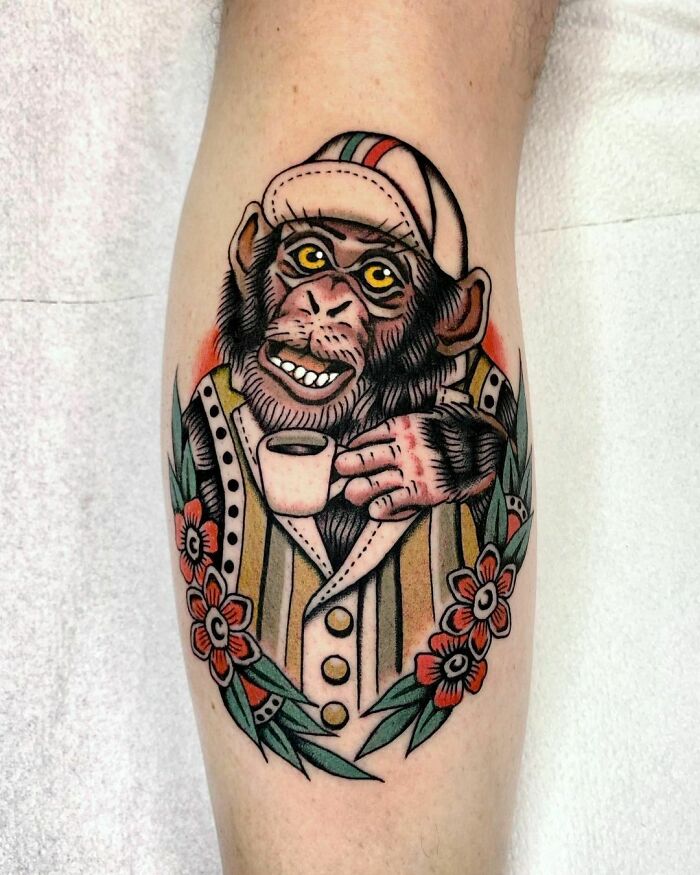American traditional tattoo of a monkey in a hat, holding a cup with floral embellishments.