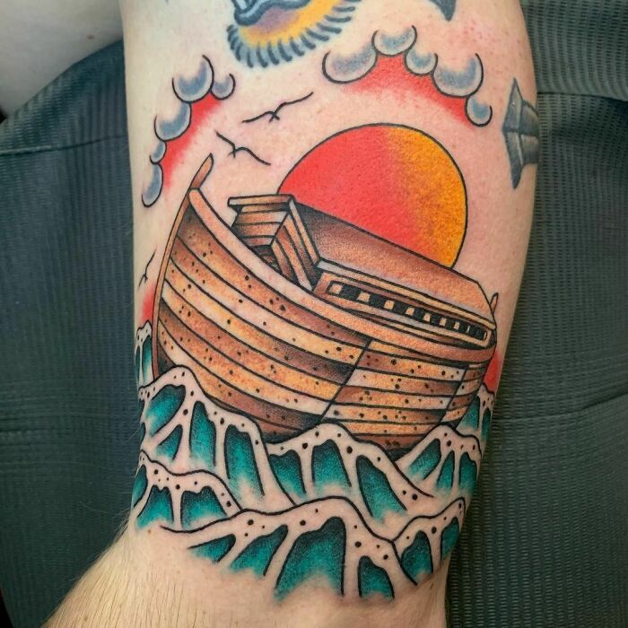 American traditional tattoo of a ship sailing on waves with a vibrant sun background.