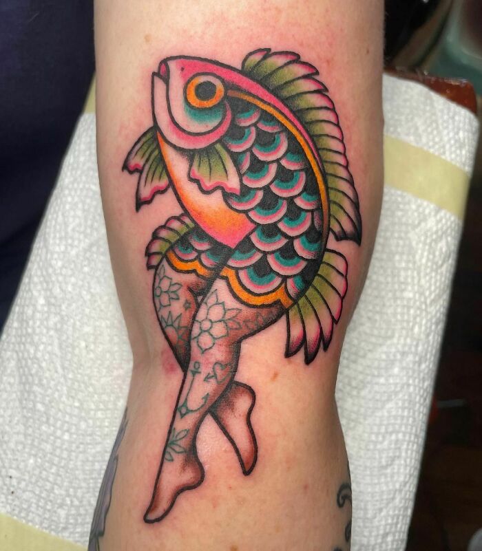 American traditional tattoo of a colorful fish with floral-patterned legs on an arm.