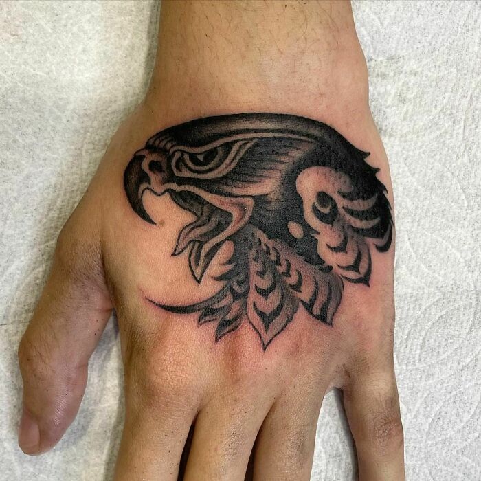 American traditional tattoo of an eagle head on a person's hand, showcasing bold lines and shading.