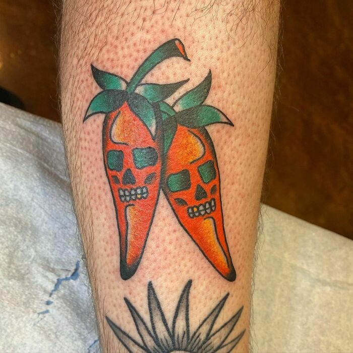 American traditional tattoo of two chili peppers with skull faces on an arm.