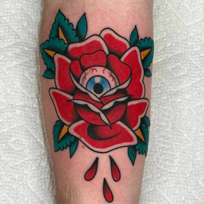 American traditional tattoo of a red rose with an eye in the center, dripping petals.