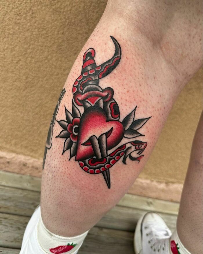American traditional tattoo with a heart and snake design on a person's leg.