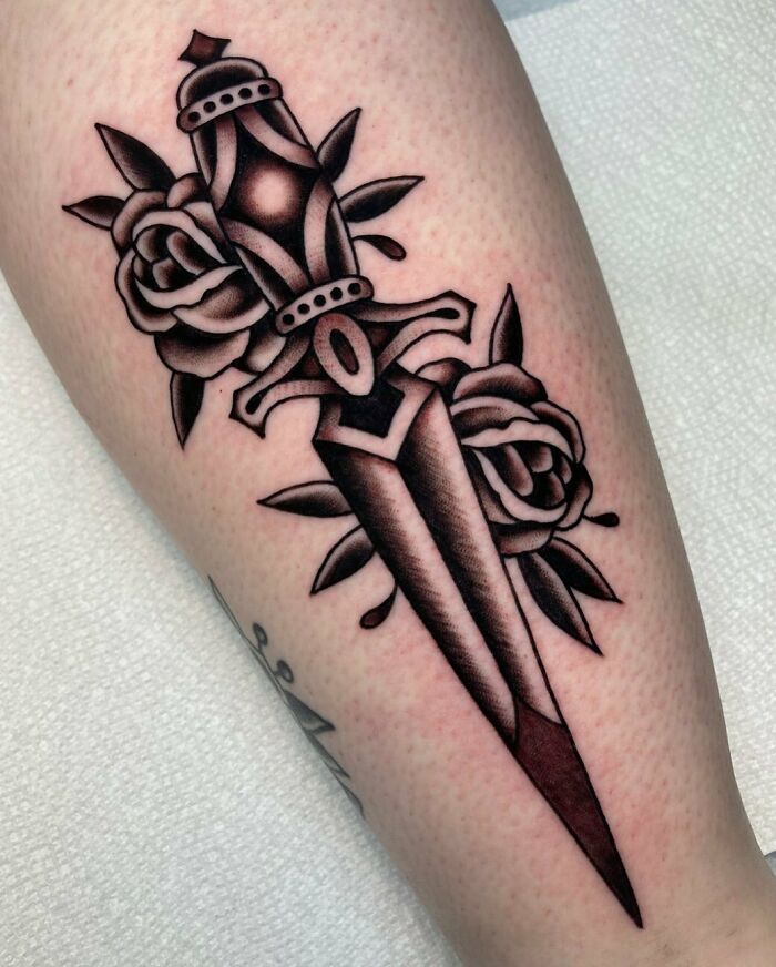American traditional tattoo of a dagger with roses on skin, showcasing bold lines and classic design.