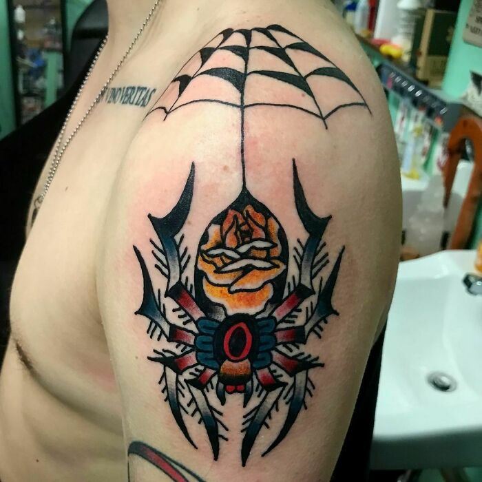 American traditional tattoo of a spider and web on upper arm, showcasing bold colors and classic design.