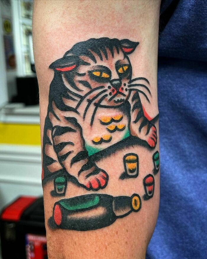 American traditional tattoo of a cat with colorful patterns and a bottle design on an arm.