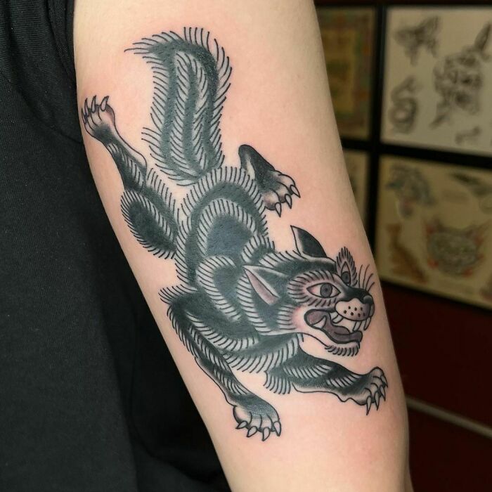 American traditional tattoo of a snarling black cat on a forearm, showcasing bold lines and classic design.