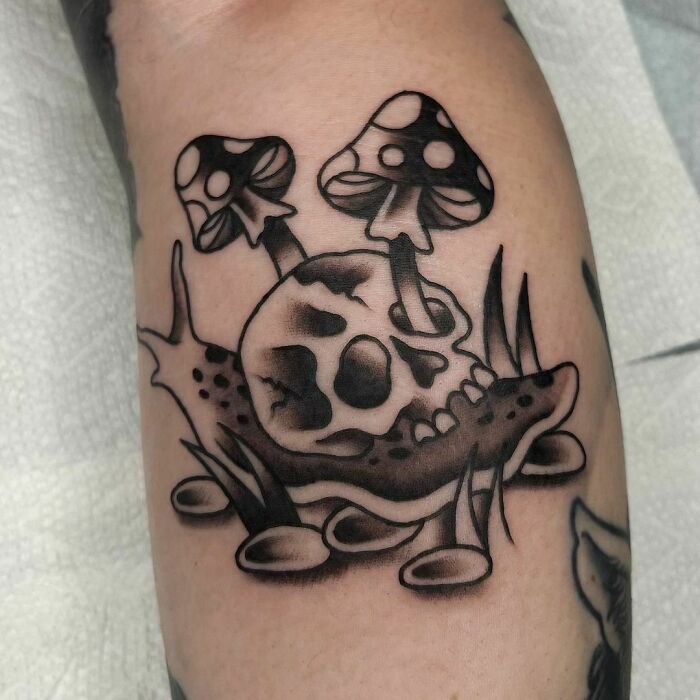 American traditional tattoo of a skull with mushrooms, showcasing bold black outlines and intricate shading.