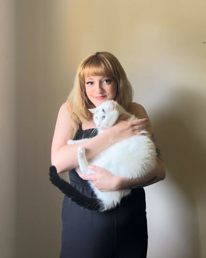 Người phụ nữ ôm một con mèo trắng có đuôi và lông mày đen
