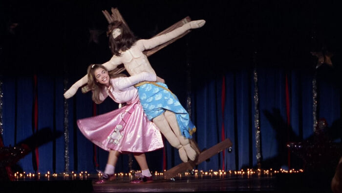 Denise Richards dancing with a stuffed doll Jesus on stage in Drop Dead