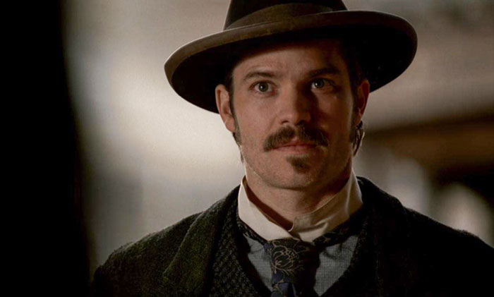 Man looking at someone with mustache and a hat 