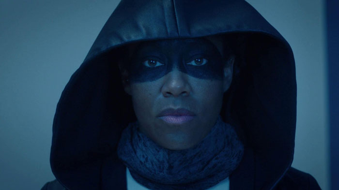 Woman with a hoodie and painted face in a dark place 