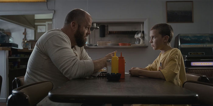 Jim Hopper and kid sitting from Stranger Things Chapter One: The Vanishing Of Will Byers