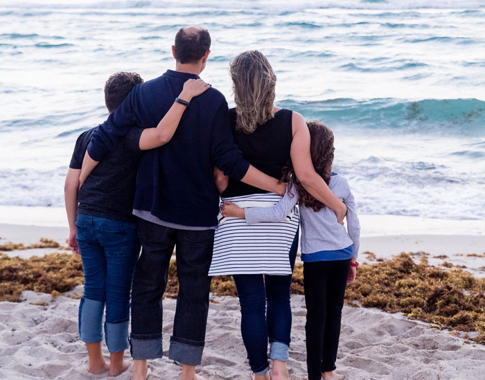 Family of four hugging on the beach 