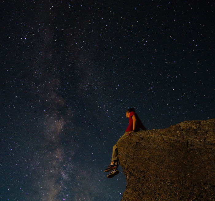 Man sitting on a cliff at night 