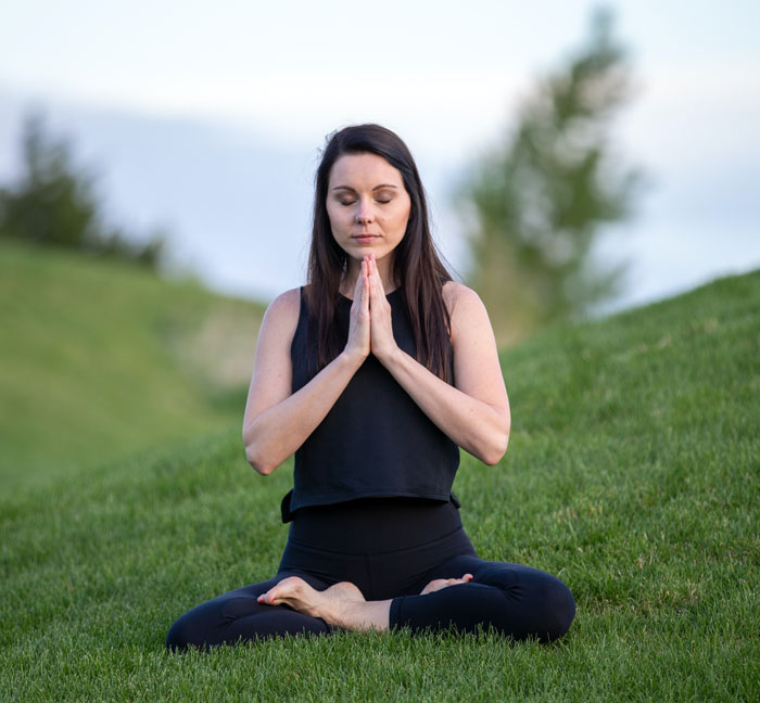 Woman meditating in a grass field 