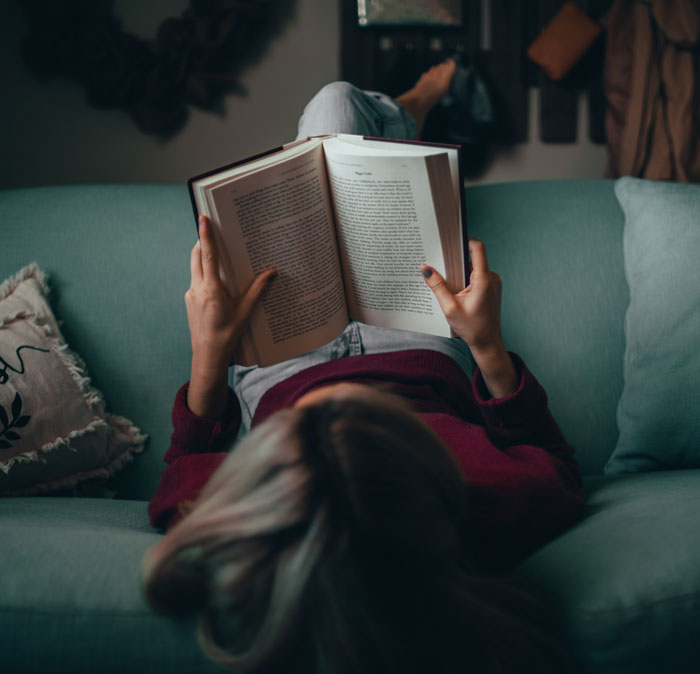 Woman sitting on sofa and reading a book 