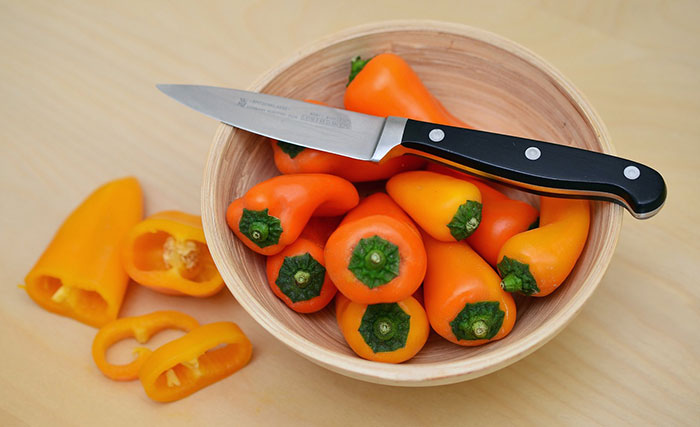 Bowl of orange paprika and knife on top