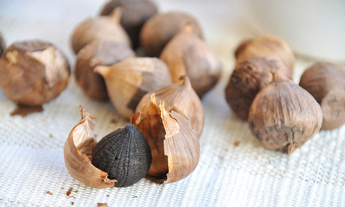 Black garlic heads on linen background
