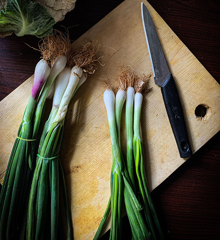 Green and white vegetables on brown wooden chopping board