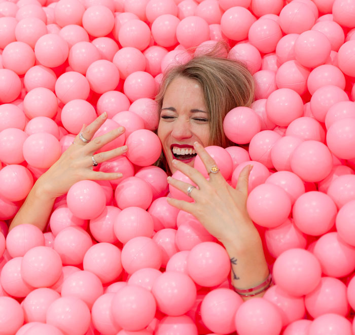 a woman lying in pink soft balls