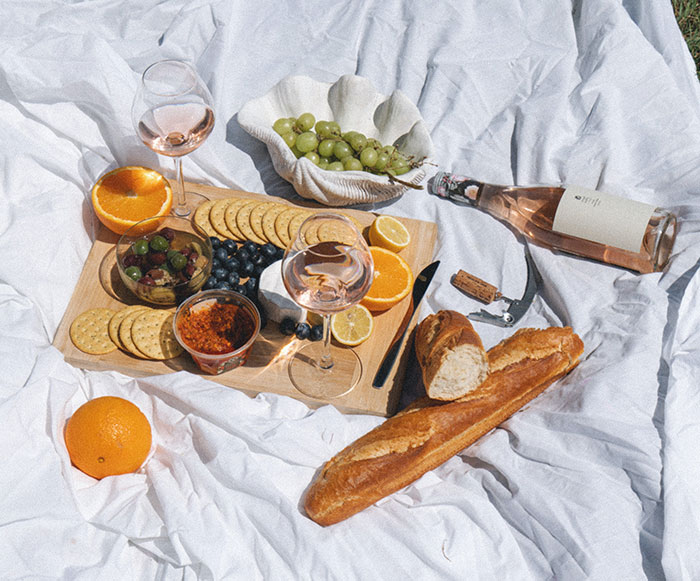 Picnic with wine and bread, fruits in the bed