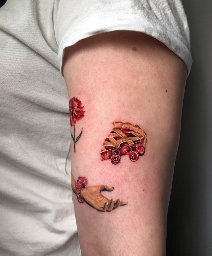 Watercolor tattoo of cherry pie and hand on arm, showcasing creative food-inspired ink art.
