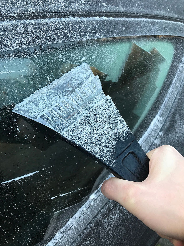 Man cleaning ice from the car window with ice scraper