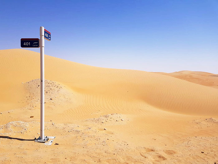 A Street Sign In The Desert, At An Intersection Of Two Sand Lanes