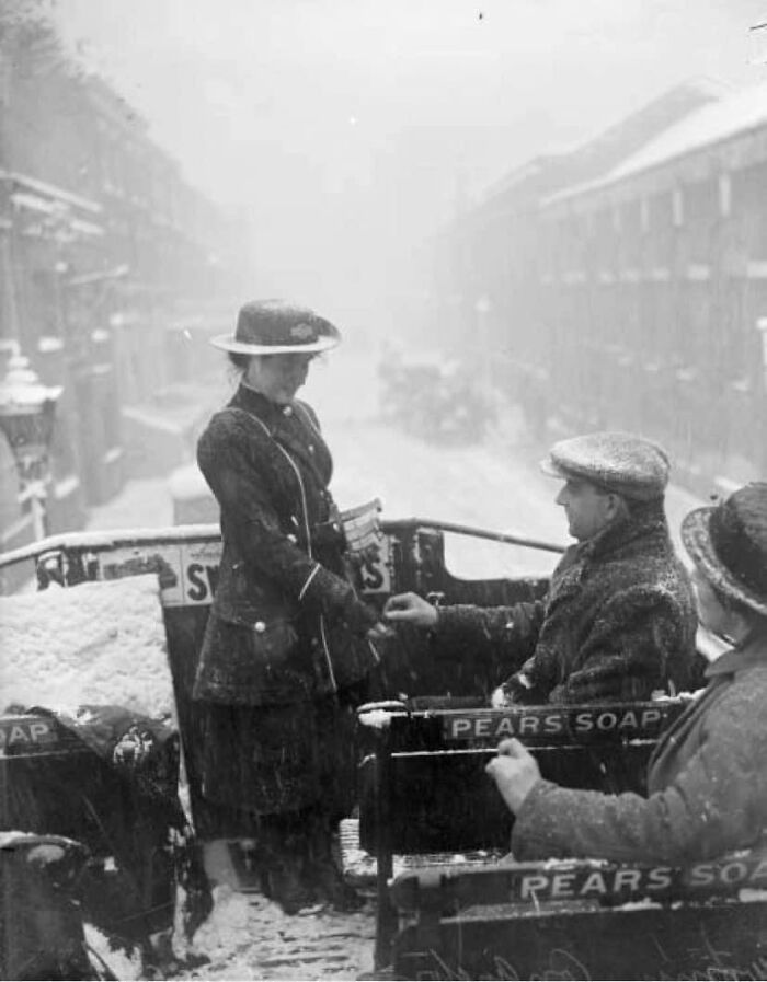 A Bus Conductress At Work On The Top Deck Of An Open Top Bus In The Snow During World War L