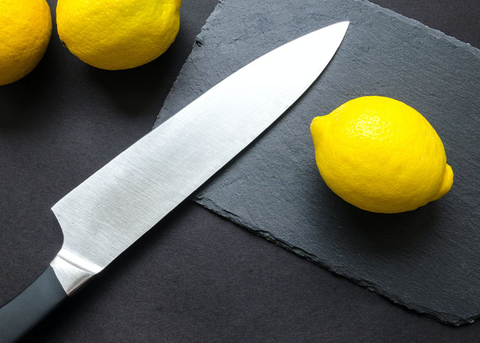 Kitchen knife and lemons on table