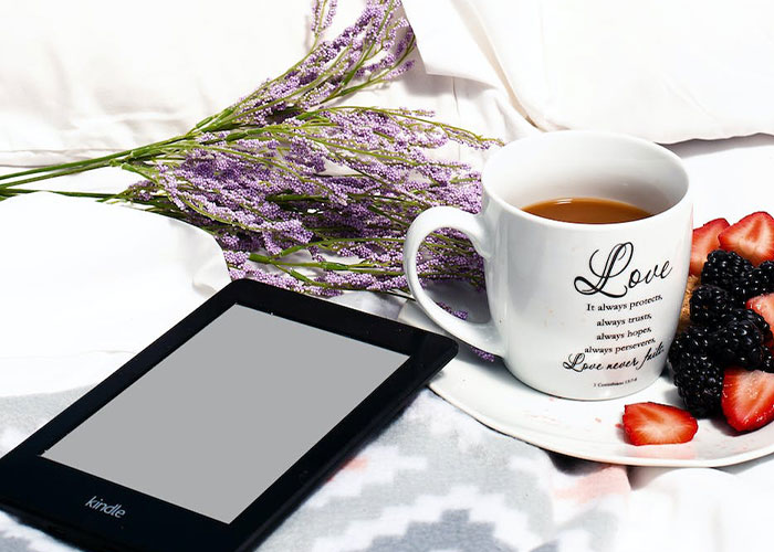 Kindle tablet on table near bouquet of lavenders and cup of tea