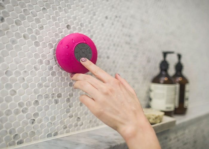 Woman touching a pink Bluetooth shower speaker