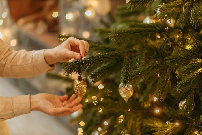 Person putting a Christmas decoration on the Christmas tree 