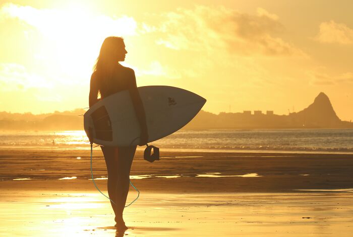 Woman standing with a surfboard in the beach 
