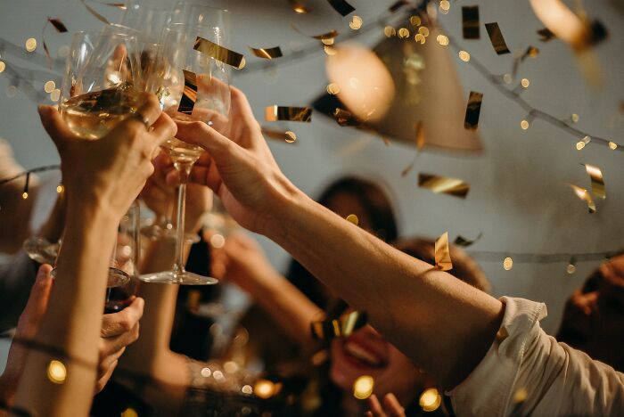 Multiple people celebrating and raising a champagne glass 